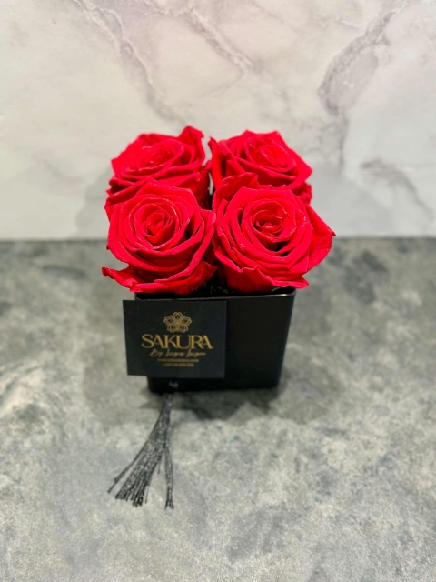 4 red preserved roses in a glass black pot